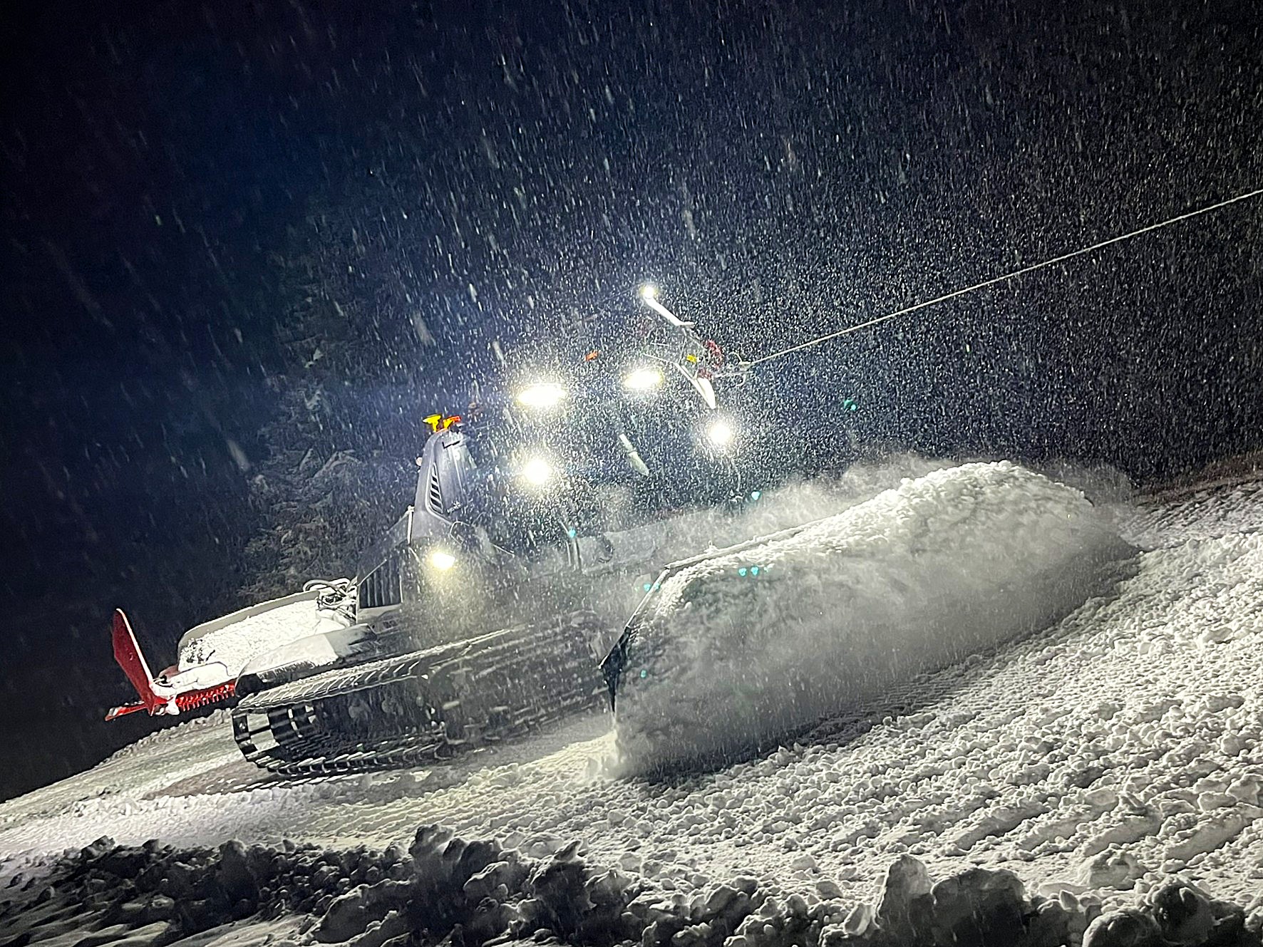 Pistenraupe bei Nacht im dichten Schneefall